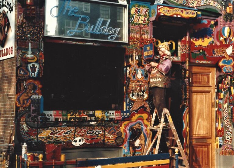 Artist Harold “Kangaroo” Thornton standing on a ladder, painting the psychedelic exterior of The Bulldog coffeeshop in Amsterdam.