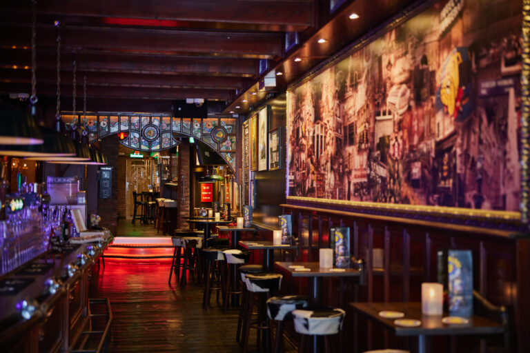 Interior of The Bulldog Amsterdam bar with wooden ceiling, lounge tables, stools and warm lighting. Image for why does cannabis sometimes smell like beer?